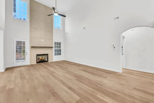 a view of an empty room with wooden floor and a fireplace