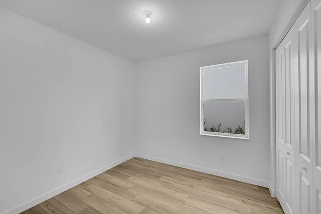 an empty room with wooden floor and a window