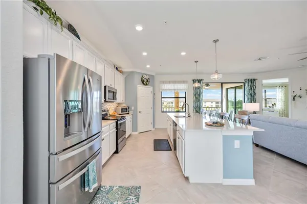 a kitchen with stainless steel appliances kitchen island granite countertop a refrigerator oven a sink a dining table and chairs with wooden floor