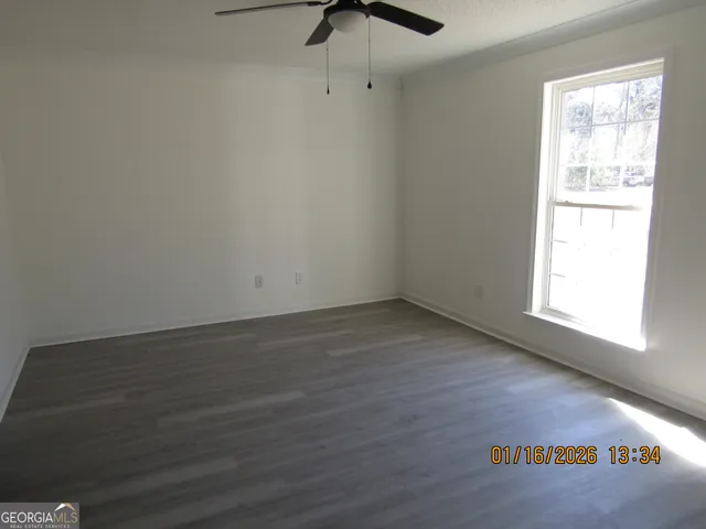 a view of an empty room with wooden floor and a window