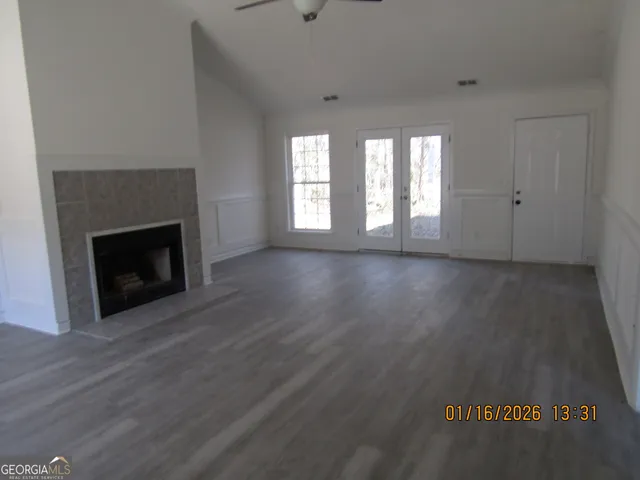 a view of an empty room with wooden floor fireplace and a window