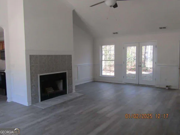 an empty room with wooden floor fireplace and windows