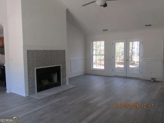 an empty room with wooden floor fireplace and windows