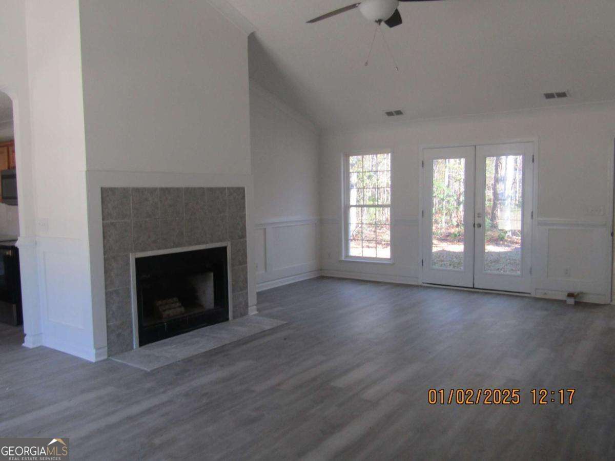 7358 Stilson-Leefield Road Brooklet, GA 30415 - Photo 4 of 24 an empty room with wooden floor fireplace and windows