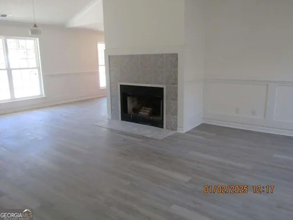 an empty room with wooden floor fireplace and windows