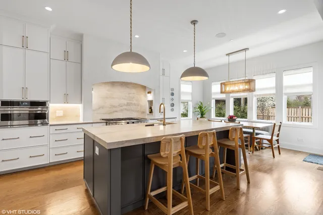 a kitchen with stainless steel appliances granite countertop a stove a sink a dining table and chairs with wooden floor