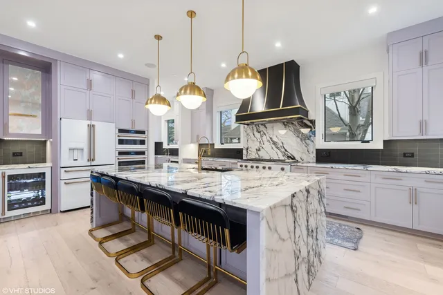 a kitchen with kitchen island granite countertop a stove a sink a oven and a refrigerator