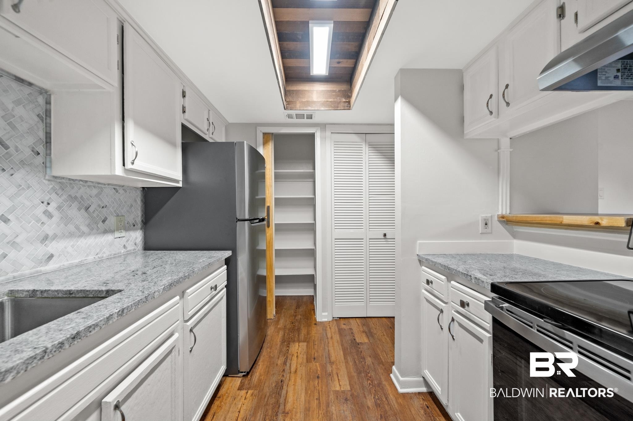 2901 Grant Street, Unit 802 Mobile, AL 36606 - Photo 14 of 37 Kitchen with white cabinets, decorative backsplash, light stone counters, dark hardwood / wood-style floors, and appliances with stainless steel finishes