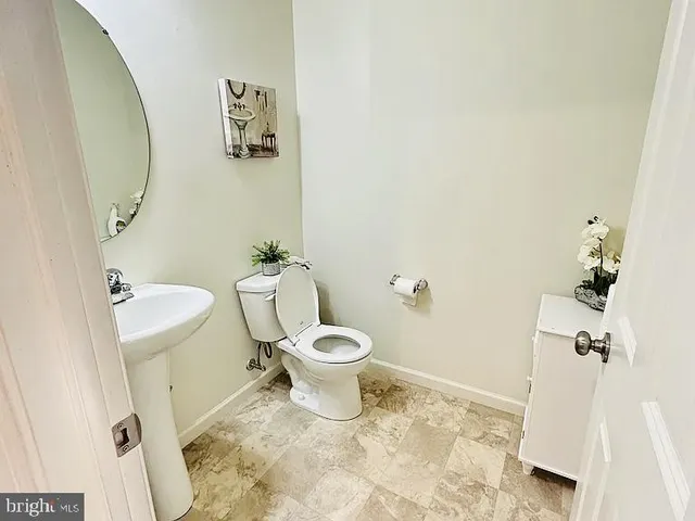 a white toilet sitting next to a bathroom sink and a mirror