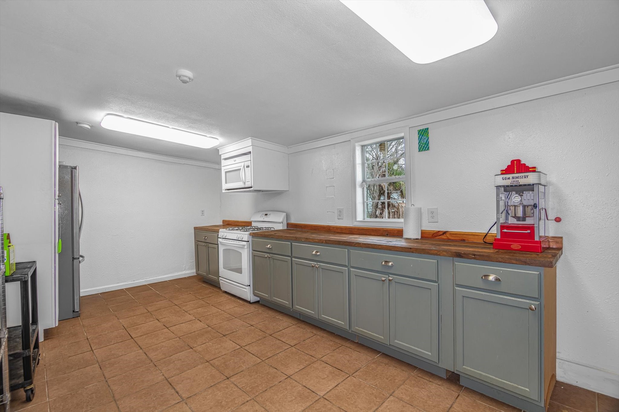 905 43rd Street Galveston, TX 77550 - Photo 19 of 43 This kitchen features ample counter space with wooden countertops and cabinets. It includes a gas stove, overhead microwave, and stainless steel refrigerator.