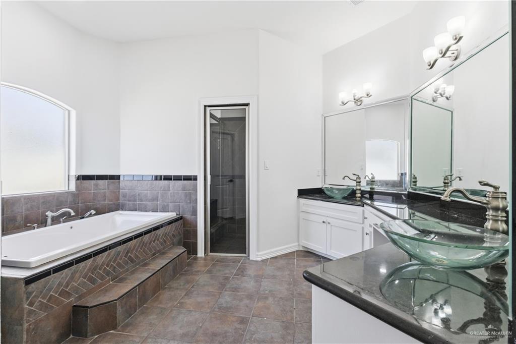 513 Mi Vida Street Weslaco, TX 78596 - Photo 17 of 22 a bathroom with a granite countertop double vanity and a bathtub