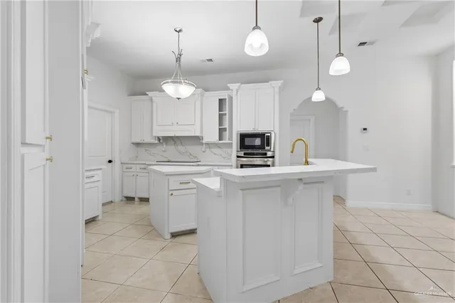 a kitchen with kitchen island granite countertop a sink a counter space appliances and cabinets