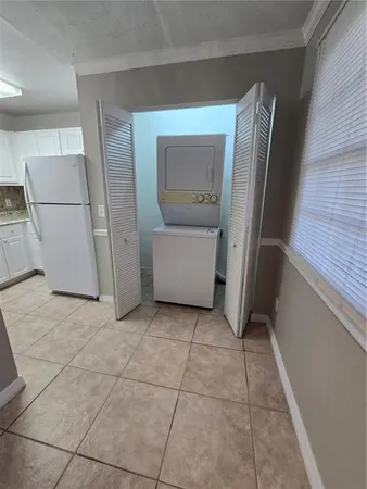 a view of a refrigerator in kitchen and an empty room