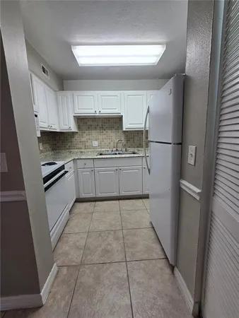 a kitchen with a sink a refrigerator and cabinets