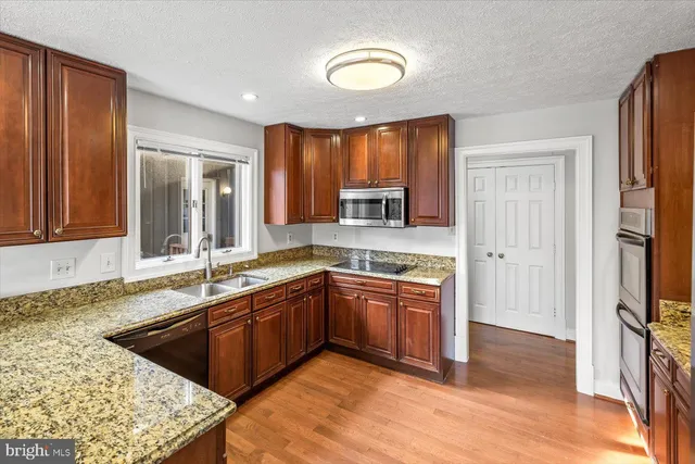 a large kitchen with stainless steel appliances granite countertop a sink and a wooden cabinets