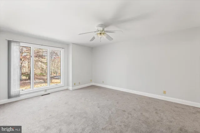 an empty room with windows and ceiling fan
