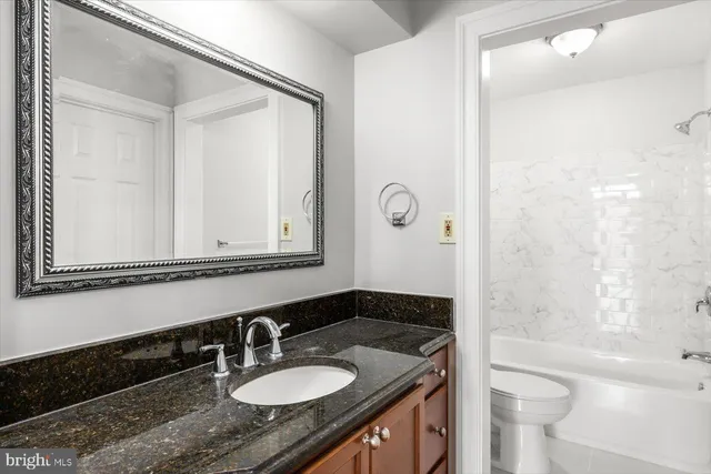 a bathroom with a granite countertop sink toilet and shower