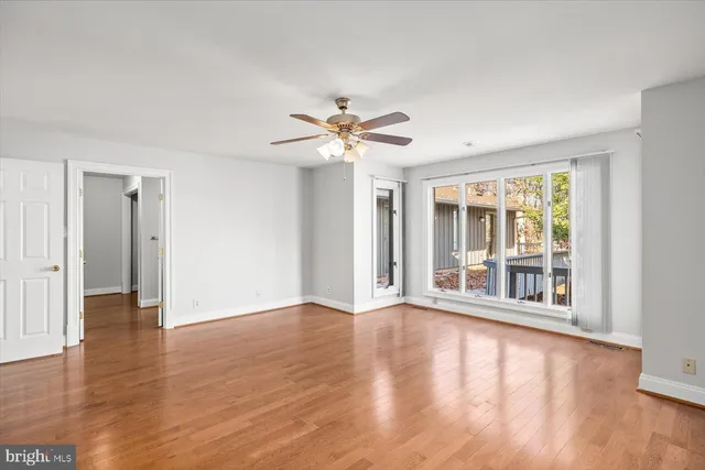 an empty room with wooden floor and a ceiling fan