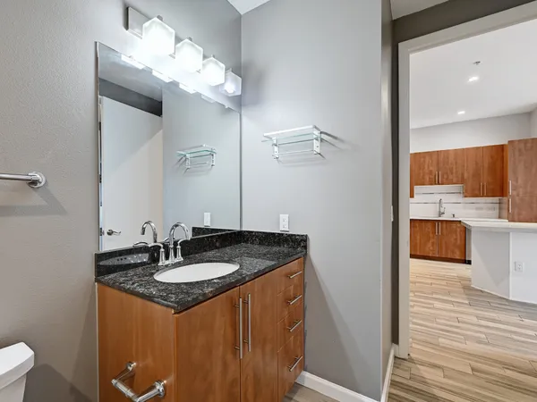 a bathroom with a granite countertop sink a toilet and mirror