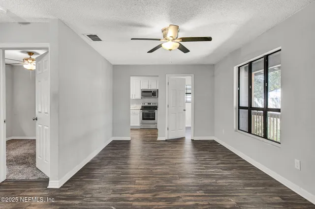 a view of an empty room with a window and wooden floor