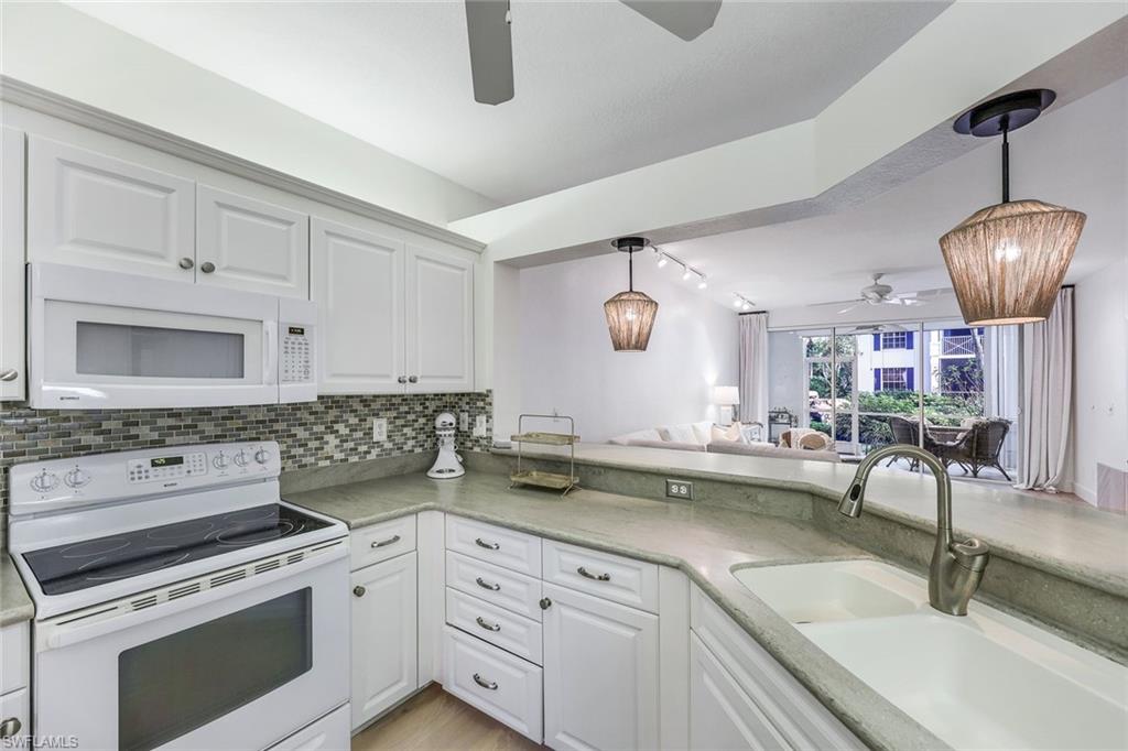7108 Barrington Circle Naples, FL 34108 - Photo 9 of 25 a kitchen with a sink dishwasher a stove and white cabinets with wooden floor