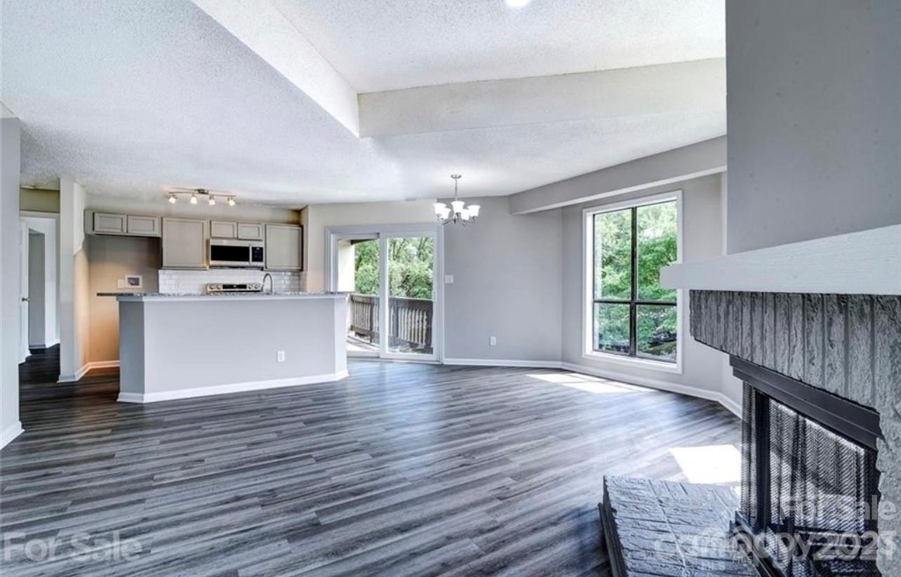a living room with stainless steel appliances furniture wooden floor and a kitchen view