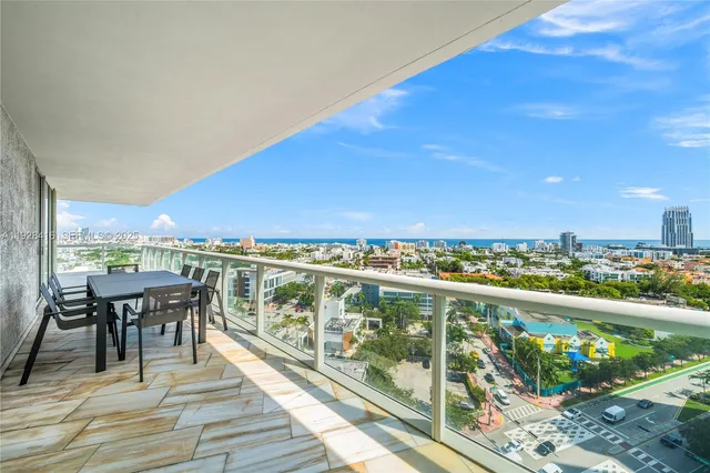 a view of a city from a balcony with dining table & chairs