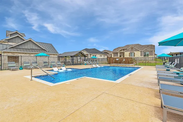 a view of swimming pool with lounge chairs in patio