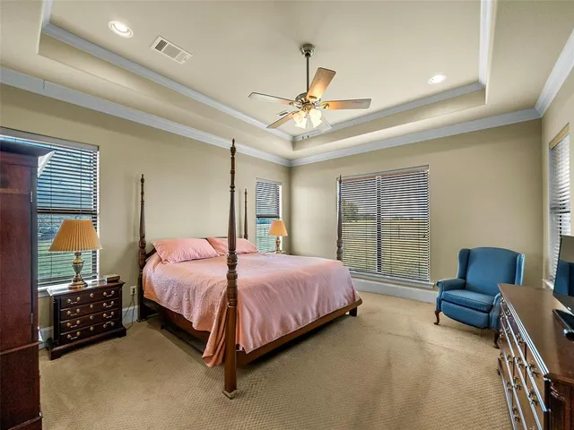 a spacious bedroom with a bed a chandelier and balcony