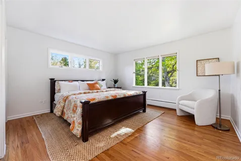 a large bedroom with wooden floor and window
