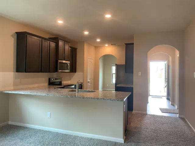 a view of a kitchen with kitchen island a sink stainless steel appliances and cabinets