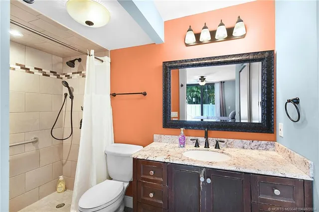 a bathroom with a granite countertop sink toilet and shower
