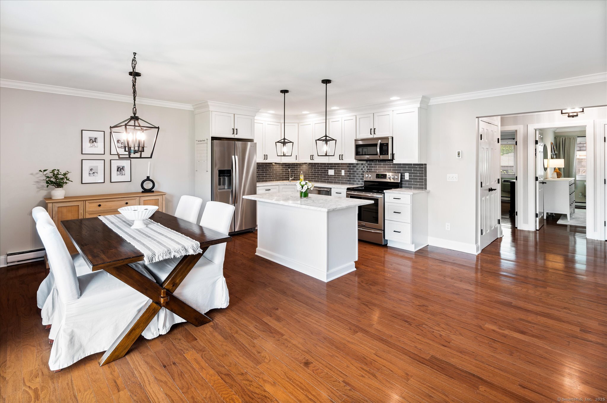 a open kitchen with stainless steel appliances granite countertop a stove top oven a refrigerator a sink and a dining table with wooden floor