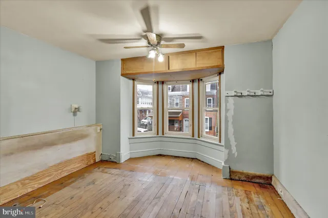 an empty room with wooden floor fan and windows