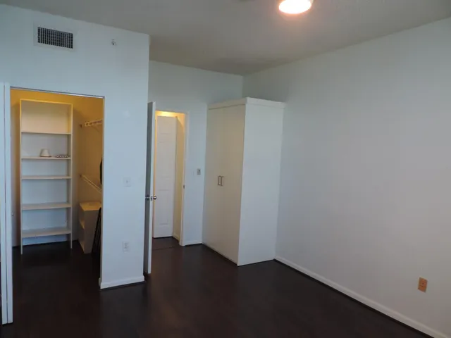 an empty room with wooden floor closet and windows