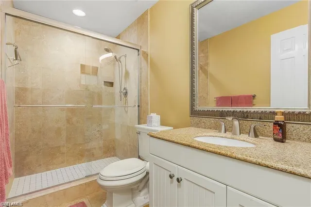 a bathroom with a granite countertop sink a toilet and shower