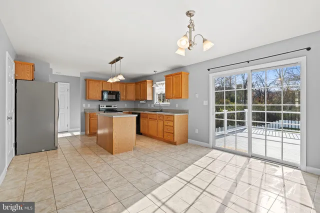 a kitchen with stainless steel appliances granite countertop a sink a stove top oven a refrigerator cabinets and a window