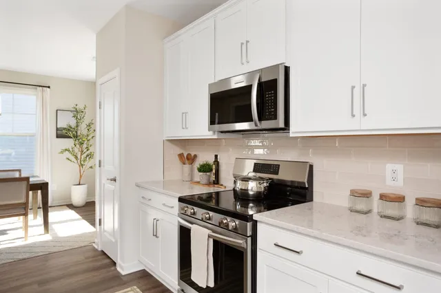 a kitchen with stainless steel appliances granite countertop white cabinets a stove a microwave and a refrigerator
