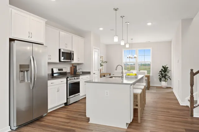 a kitchen with stainless steel appliances a stove top oven a refrigerator a sink and dishwasher with wooden floor