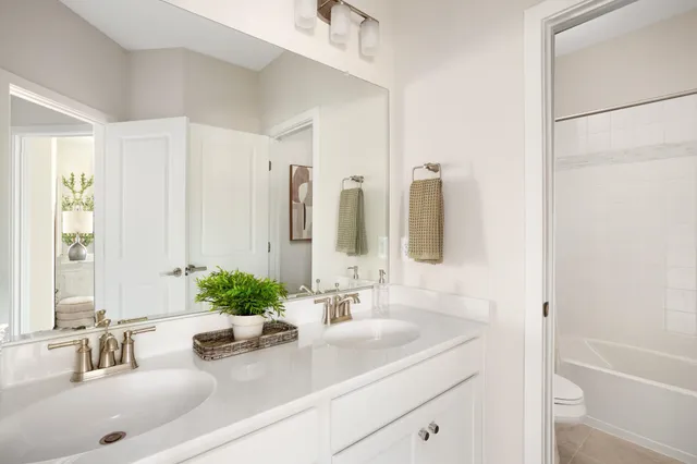 a bathroom with a double vanity sink a mirror and a bathtub