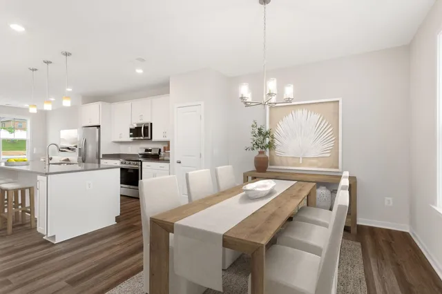 a kitchen with stainless steel appliances kitchen island granite countertop a table chairs and a refrigerator