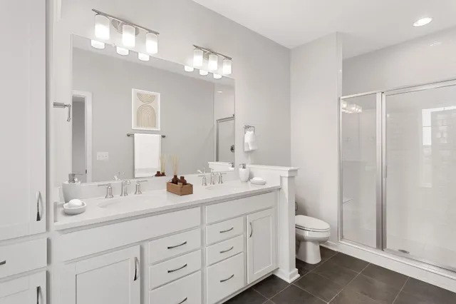 a bathroom with double vanity sink a toilet and a large mirror