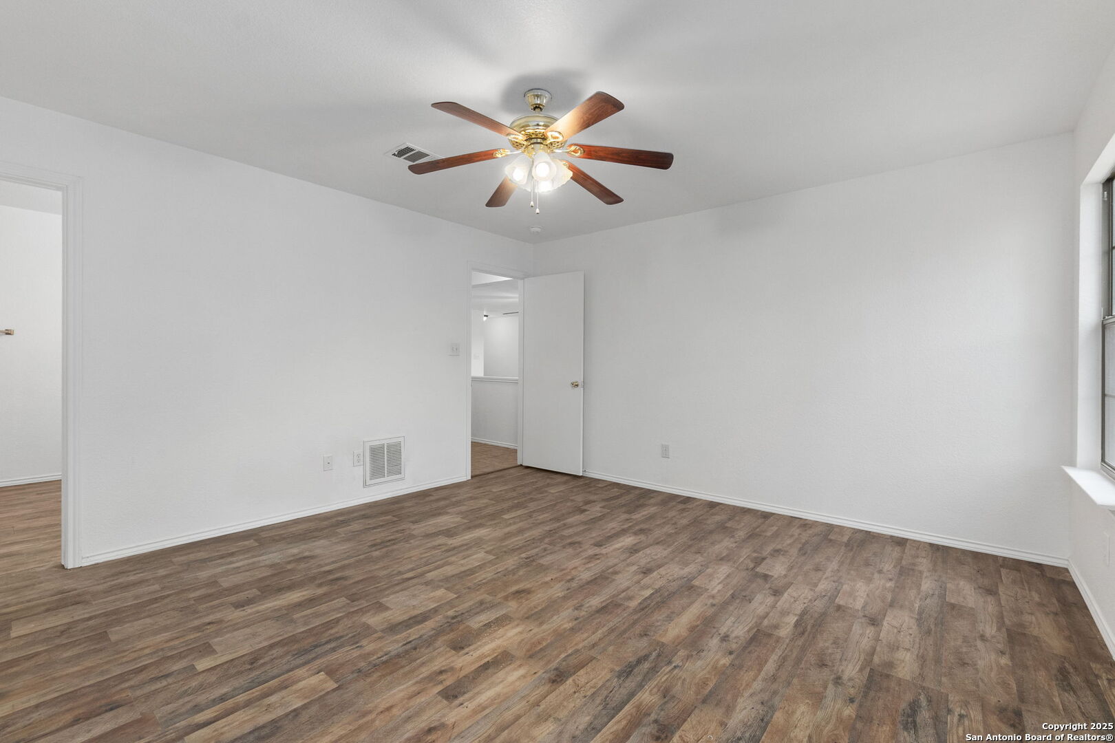 620 Waterleaf Boulevard Kyle, TX 78640 - Photo 10 of 34 an empty room with wooden floor fan and windows