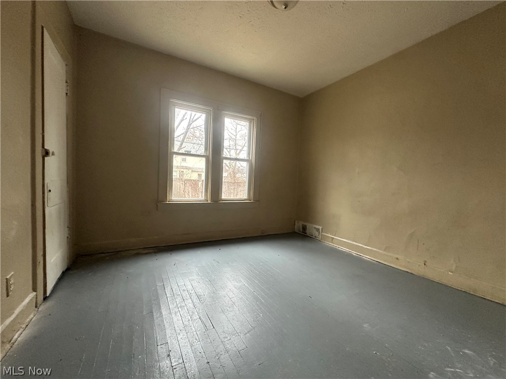 13510 Coit Road Cleveland, OH 44110 - Photo 7 of 12 Unfurnished room with wood-type flooring and a textured ceiling