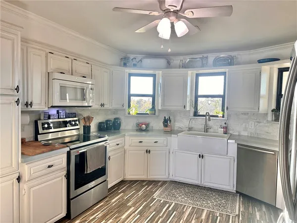 a kitchen with cabinets stainless steel appliances a sink and a window