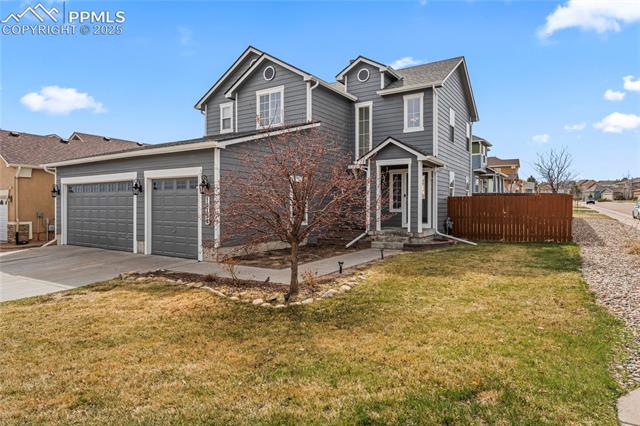 10158 Angeles Road Peyton, CO 80831 - Photo 2 of 43 Traditional-style home featuring a garage, driveway, fence, and a front lawn