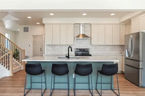 a kitchen with stainless steel appliances a table chairs refrigerator and cabinets