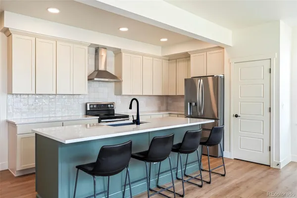 a kitchen with stainless steel appliances a sink a stove a refrigerator cabinets and dining table