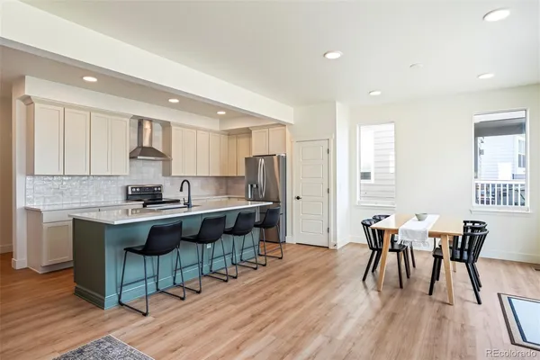a kitchen with a dining table chairs and wooden floor