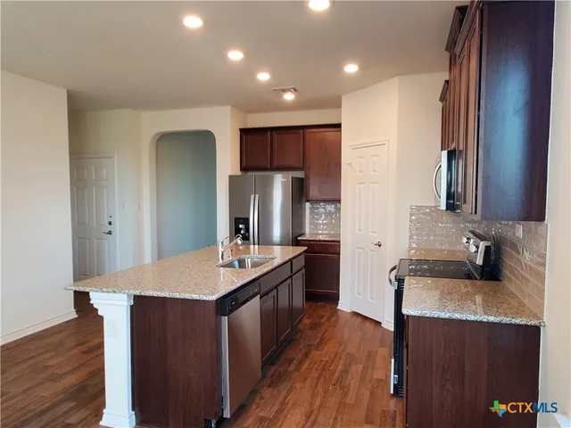 a kitchen with stainless steel appliances granite countertop a sink stove and refrigerator